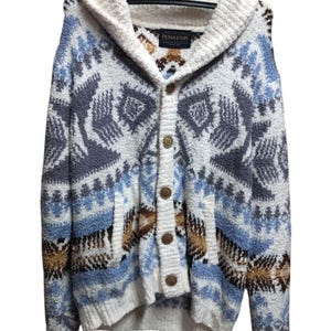 May include: A hooded cardigan sweater with a button-up front. The sweater features a geometric pattern in shades of blue, brown, and gray on a white background. The label "PENDLETON" is visible on the inside of the collar.