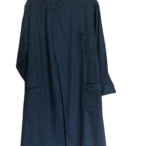 May include: A dark navy blue long coat with a unique asymmetrical design. The coat features a mandarin collar, a single button closure, and two front pockets. The fabric appears to be a soft, woven material.