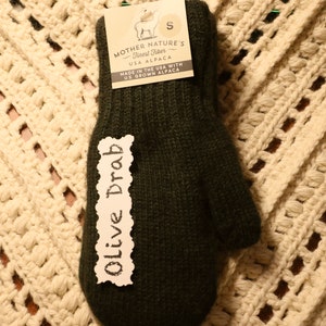 K&ouml;nnte beinhalten: Olive Drab Alpaka-Handschuhe mit einem Gr&ouml;&szlig;enetikett S. Das Etikett lautet "Mother Nature's Finest Fiber USA Alpaca Made in the USA with U.S. Grown Alpaca".