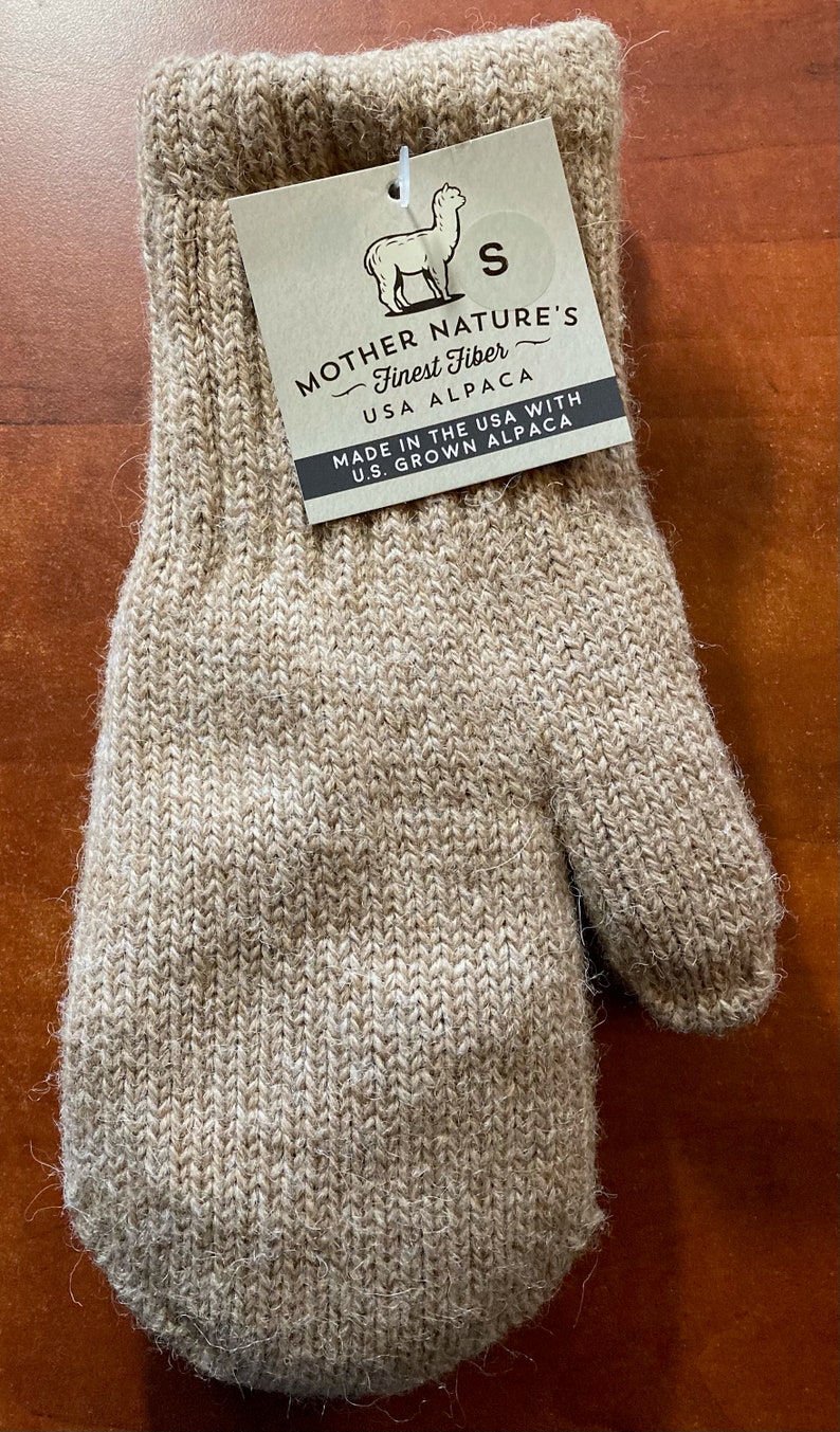 K&ouml;nnte beinhalten: Ein Paar beigefarbene Alpaka-Handschuhe mit einem Etikett mit der Aufschrift "Mother Nature's Finest Fiber - USA Alpaca. Made in the USA with U.S. Grown Alpaca". Das Etikett zeigt eine kleine Alpaka-Illustration und die Gr&ouml;&szlig;e "S".