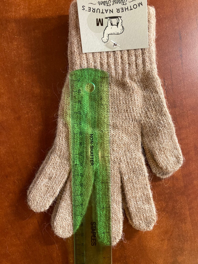 May include: A pair of beige alpaca gloves with a size M tag attached. The tag reads "Mother Nature's Finest Fiber".