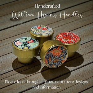 May include: Handcrafted William Morris handles. Four brass cabinet knobs with floral patterns in red, blue, and green. The knobs have a gold finish and are on a wooden surface. Text reads "Please look through all photos for more designs and information."