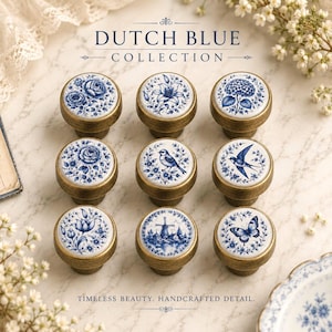 May include: A set of nine round cabinet knobs with antique brass bases and white ceramic tops featuring blue floral, bird, butterfly, and windmill illustrations. The text DUTCH BLUE COLLECTION and TIMELESS BEAUTY. HANDCRAFTED DETAIL. is visible.