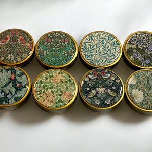 May include: Eight round, gold-rimmed coasters featuring various floral and bird designs in shades of green, blue, pink, and white.