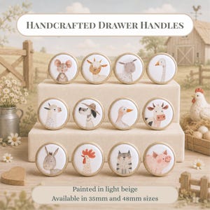 May include: Twelve round drawer handles with gold-toned metal rims, each featuring a unique watercolour illustration of a farm animal including a mouse, goat, sheep, goose, llama, dog, duck, cow, donkey, rooster, cat, and pig. Text reads Handcrafted Drawer Handles.