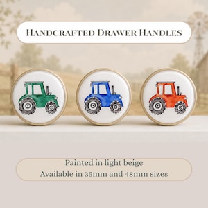 Puede incluir: Tres tiradores de cajón redondos con bordes beige claro y centros blancos. Cada tirador presenta una ilustración de tractor estilo acuarela en verde, azul o rojo. Texto: HANDCRAFTED DRAWER HANDLES, Painted in light beige, Available in 35mm and 48mm sizes.