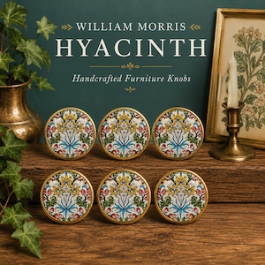 May include: Six round furniture knobs featuring a William Morris Hyacinth floral pattern in yellow, red, blue, and green on a white background, encased in a gold-toned metal rim. The text reads WILLIAM MORRIS HYACINTH Handcrafted Furniture Knobs.
