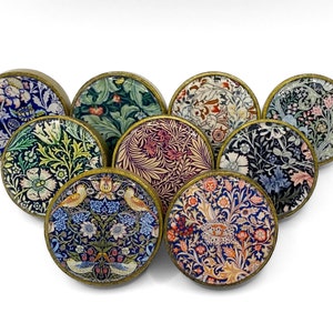May include: A set of nine round, brass-coloured knobs with a variety of floral patterns in shades of blue, green, pink, and red.