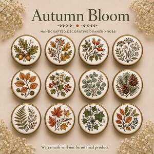 Peut inclure: Un ensemble de douze boutons de tiroir ronds avec des bords en métal doré, chacun présentant une illustration botanique unique sur fond blanc. Les motifs incluent des glands, des baies, des pommes de pin, des fougères et des feuilles.