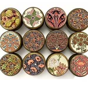 Puede incluir: Doce pomos redondos de color latón con una variedad de diseños florales y botánicos. Cada pomo presenta un patrón diferente en tonos de rosa, rojo, verde, azul y amarillo.