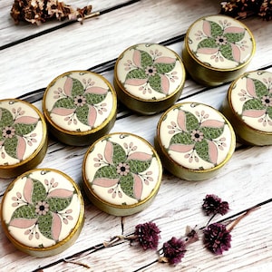 May include: Eight round, decorative knobs with a floral design. The knobs are painted with a white background, pink and green floral pattern, and a gold rim.