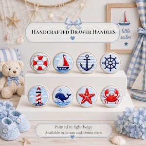 Puede incluir: Ocho tiradores de cajón redondos de madera con ilustraciones náuticas que incluyen un salvavidas, velero, ancla, timón, faro, ballena, estrella de mar y cangrejo. El texto dice Handcrafted Drawer Handles, Painted in light beige, Available in 35mm and 48mm sizes.