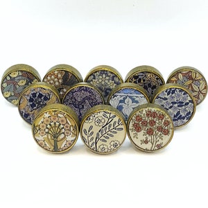 May include: Assortment of 10 round, brass-colored cabinet knobs with floral patterns. The knobs feature a variety of colors, including blue, purple, yellow, and red.
