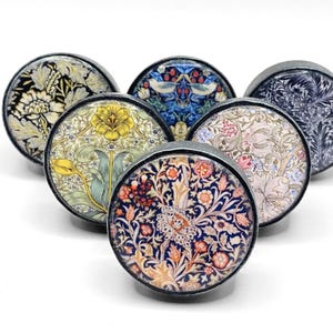 May include: Six round, decorative cabinet knobs with a silver metal base and colourful floral patterns. The patterns include a blue and green floral design, a yellow and green floral design, a pink and green floral design, a blue and white floral design, a black and white floral design, and a red, orange and yellow floral design.