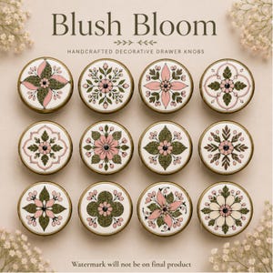 Könnte beinhalten: Zwölf runde Schubladenknöpfe mit einem messingfarbenen Metallrand und einer weißen Keramikmitte mit verschiedenen Blumenmustern in Rosa- und Grüntönen. Der Text Blush Bloom Handcrafted Decorative Drawer Knöpfe ist darüber abgedruckt.