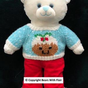 May include: A white teddy bear wearing a light blue sweater with a Christmas pudding design and red pants. The bear has blue accents on its ears and eyes, and white fur trim on its feet.