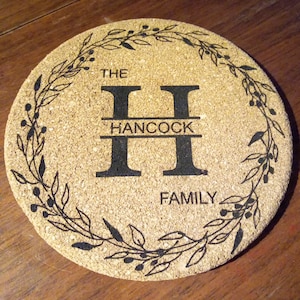 Peut inclure: Sous-verre rond en liège avec le texte "THE HANCOCK FAMILY" et un grand "H" noir. Une couronne florale noire entoure le texte. Le dessous de verre est en liège naturel.