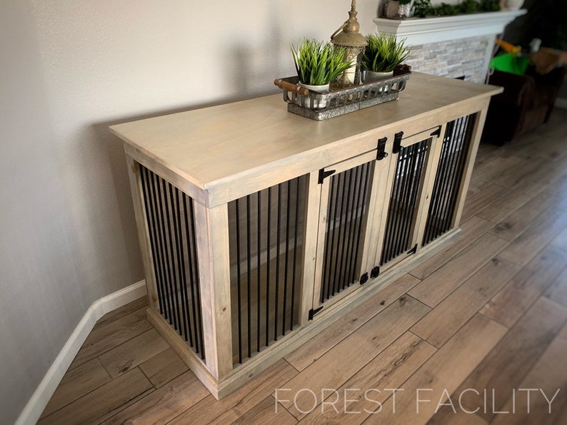 May include: A light wood dog crate with two doors and a top surface. The crate has black metal bars and black metal hinges. The top surface has a decorative tray with a small potted plant.