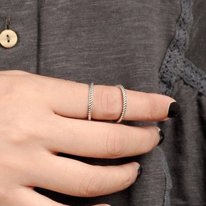 May include: Two silver rings with a twisted design worn on a finger.