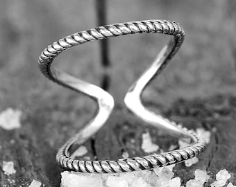 May include: A silver ring with a twisted rope design. The ring is open and can be adjusted to fit different finger sizes.
