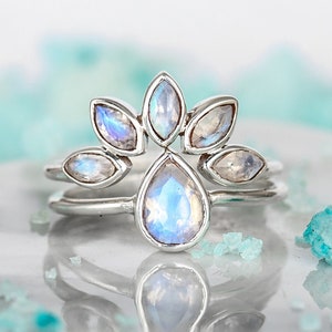 May include: A silver ring with a teardrop-shaped moonstone in the center and a halo of smaller moonstones around it.