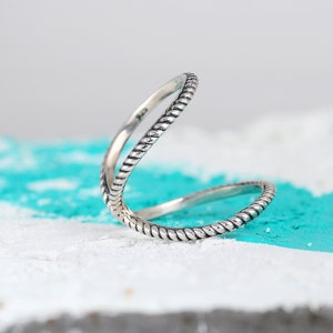 May include: A silver ring with a twisted rope design. The ring is open and can be worn on multiple fingers.