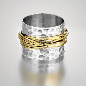 May include: A silver-colored ring with a hammered texture and a band of interwoven gold-colored wire. The ring has a wide band design and a polished finish, suitable for everyday wear.