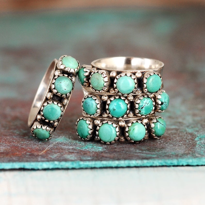 May include: Stack of four silver rings with turquoise stones. Each ring has a row of turquoise stones set in silver.