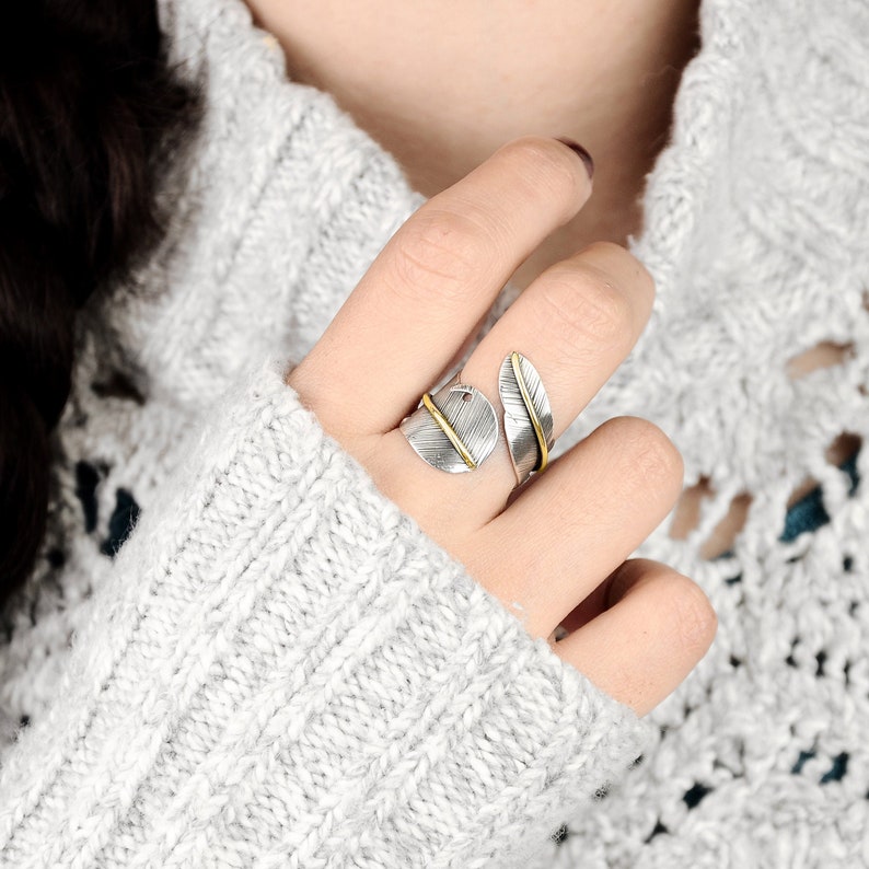 May include: A silver and gold feather ring with a delicate design. The ring is adjustable and can be worn on any finger.