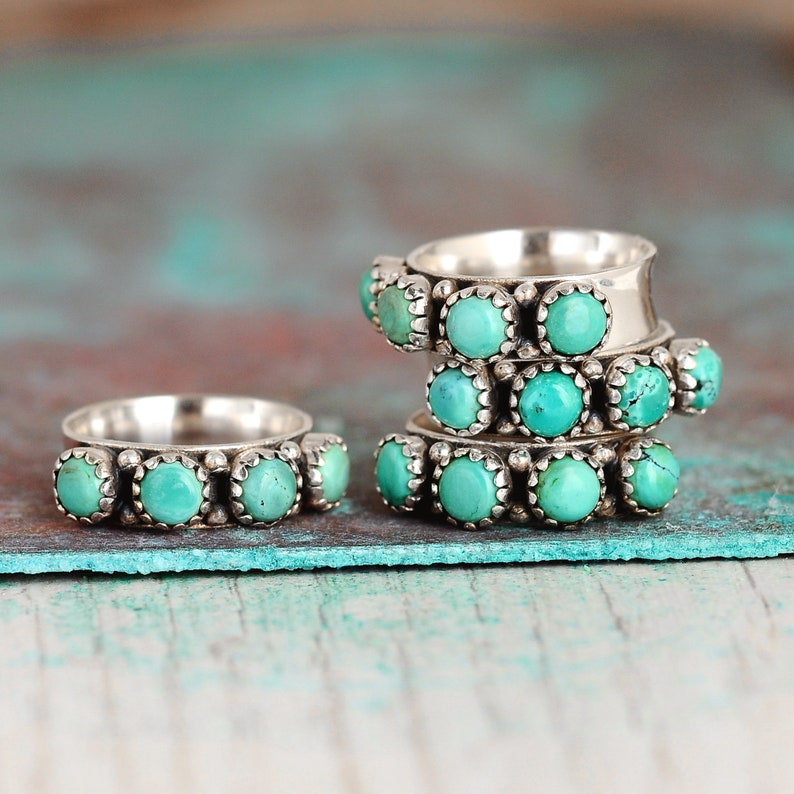 May include: Stack of four silver rings with turquoise stones. Each ring has a row of turquoise stones set in silver.