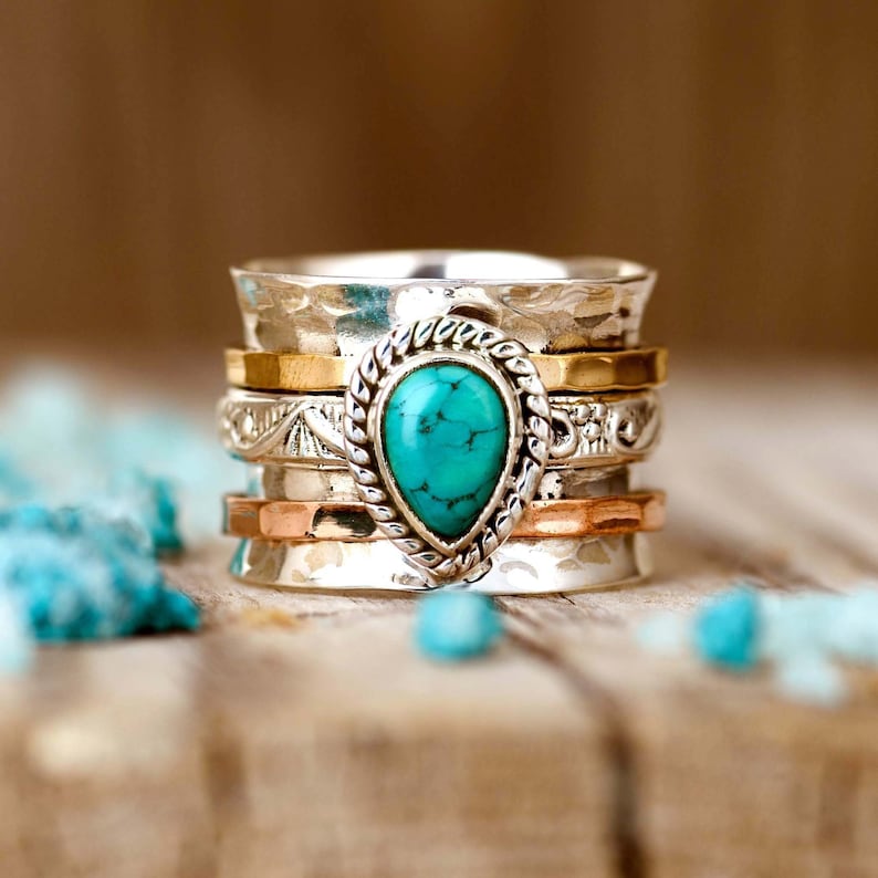 May include: A silver ring with a turquoise stone and multiple bands of silver, gold, and copper.