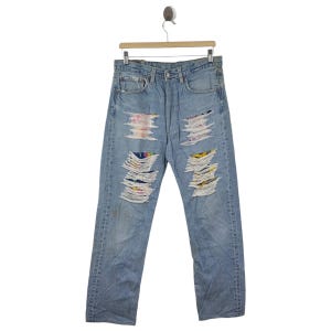 Pode incluir: Jeans de denim azul claro com vários patches de tecido colorido costurados sobre rasgos e rasgos.