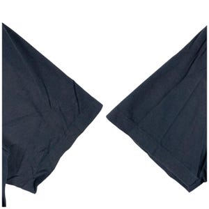 Pu&ograve; includere: Primo piano di due maniche corte blu navy scuro di una t-shirt. Le maniche sono realizzate in un tessuto morbido e strutturato e sono su uno sfondo bianco. Le cuciture sono visibili.