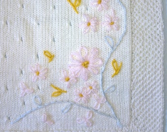 Couverture écru tricot fait main pour bébé brodée fleurs, parsemée de petits trous