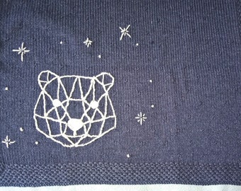 Couverture bleu Jean foncé tricot fait main pour bébé brodée d'un ourson géométrique écru, parsemée de petits picots