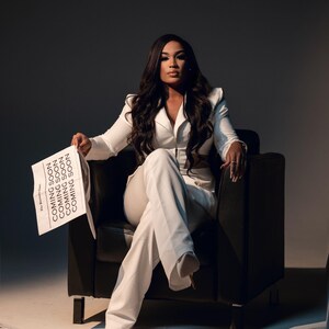 May include: A woman in a white pantsuit sits in a black leather chair, holding a newspaper with the text "Coming Soon" repeated multiple times. The newspaper is surrounded by other newspapers on the floor.