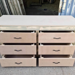 May include: A wooden workbench with six drawers. The drawers are open and have black metal handles. The workbench is made of unfinished wood.