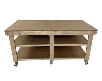 May include: A wooden workbench with two shelves and four wheels. The workbench is made of natural wood and has a light brown finish.