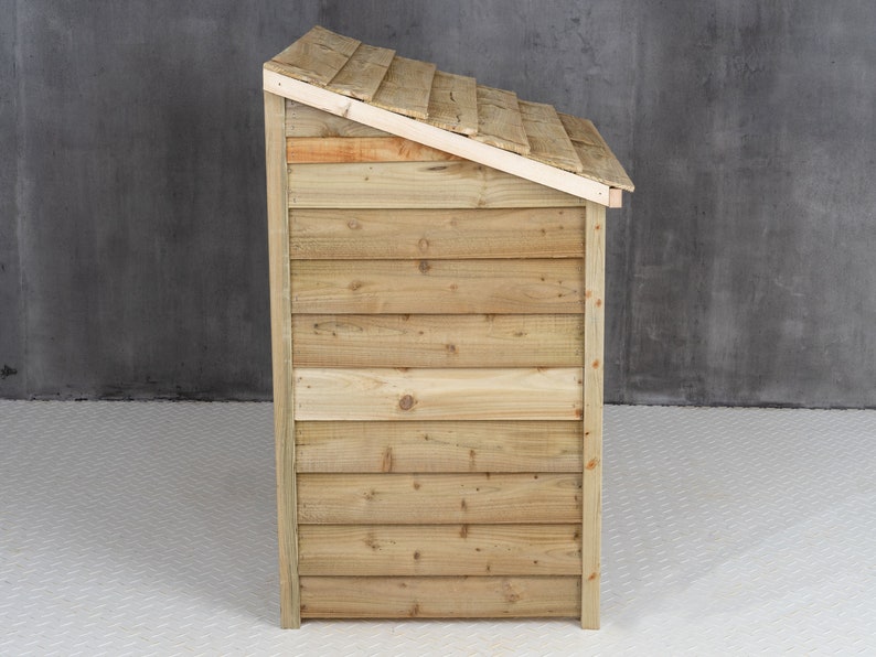 May include: Side view of a wooden storage shed with a slanted roof. The shed is made of natural wood with a light brown color.