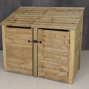 May include: A wooden double-door bin storage unit with a slanted roof. The unit has two doors with black metal latches.