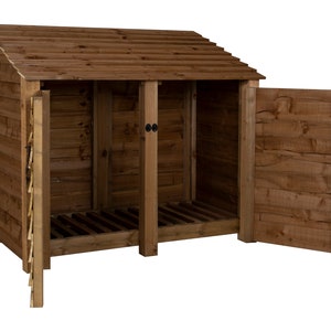 May include: A wooden log storage shed with a slanted roof and two doors. The doors are open, revealing the interior of the shed, which has a slatted floor.