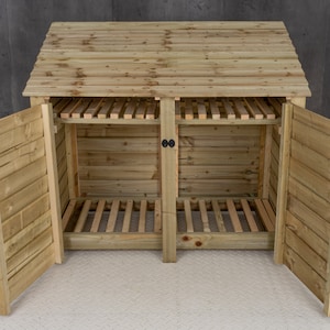 May include: A wooden log storage shed with a gabled roof and two doors. The doors are open, revealing the interior with shelves and a slatted floor.