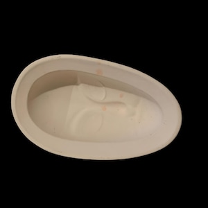 May include: White ceramic mold for making a face mask. The mold is oval shaped and has a raised design of a face with eyes, nose, and mouth.