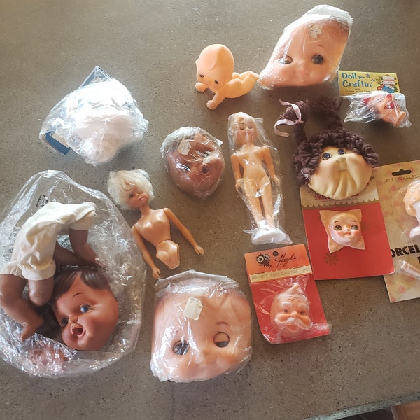 Vintage lot of 14 doll head, doll parts including kewpie doll