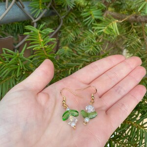May include: Green and clear glass bead earrings with gold hooks and white pearl accents.