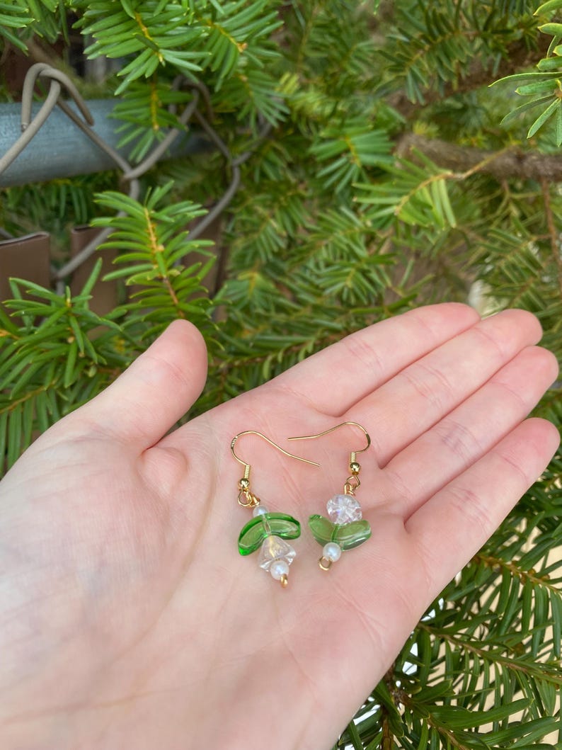May include: Green and clear glass bead earrings with gold hooks and white pearl accents.