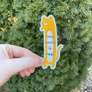 May include: A yellow cartoon cat sticker with the text "long covid is real".