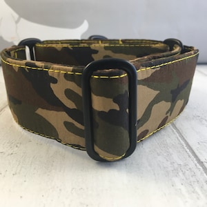 May include: A camouflage dog collar with black metal hardware and yellow stitching.