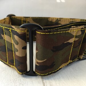 May include: A camouflage dog collar with yellow stitching and a black buckle. The collar is made by "Pickle-Butt" and is designed for dogs.