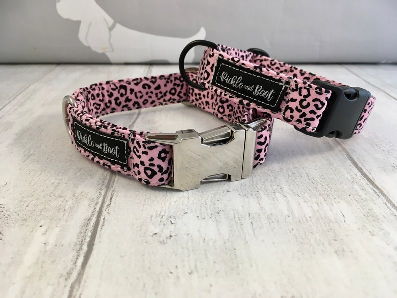 May include: Two pink and black leopard print dog collars with silver buckles. The collars have the text "Pickle and Boot" on them.